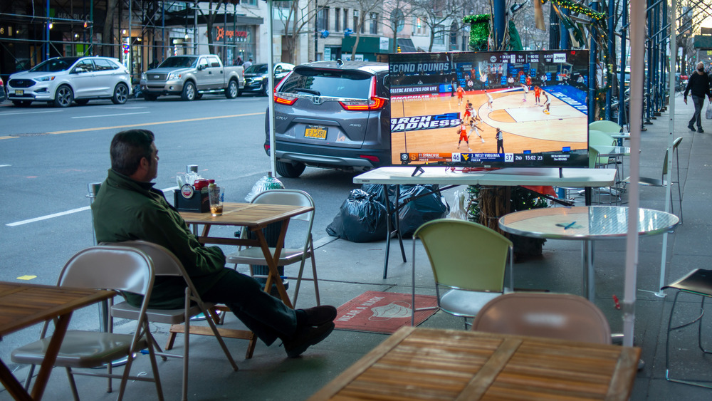 A man watching the game in an outdoor dining environment