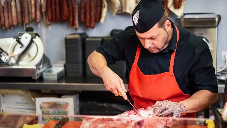 butcher cutting bone-in ham