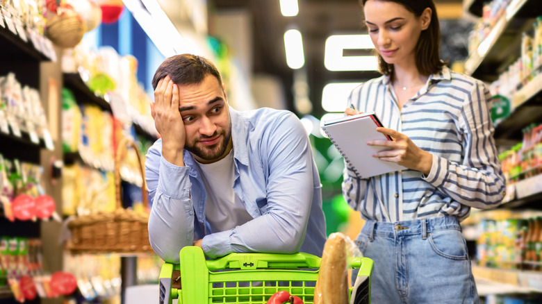 Woman with list and stressed man shopping