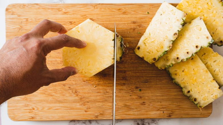 cutting off the sides of the pineapple