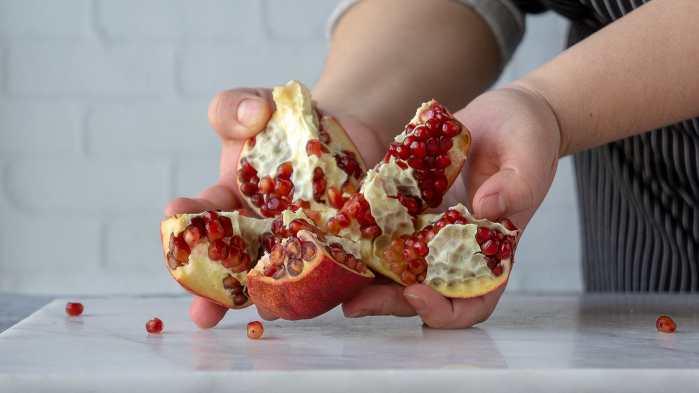 hands holding a pomegranate that was cut into wedges
