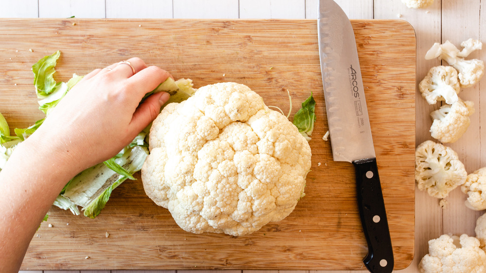 peeling leaves off cauliflower