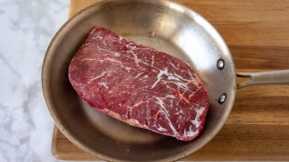 a frozen steak in a stainless steel pan