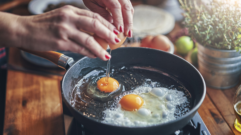 Person cracking eggs into a pan