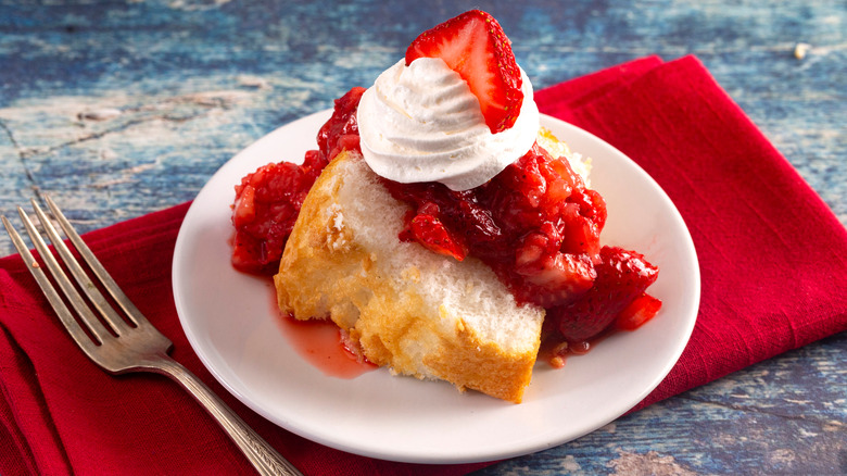 Angel food cake slice topped with whipped cream and berries