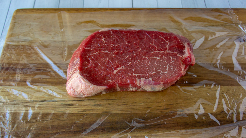 a steak sitting a layer of plastic wrap