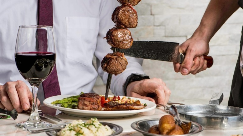 Skewer of meat being cut at restaurant table