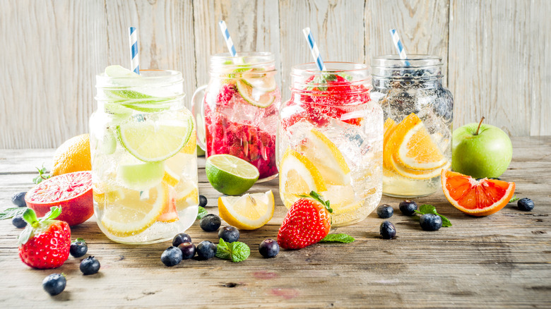 Four jars of lemonade with various fruits mixed in