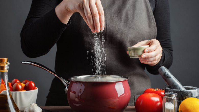 woman salting pasta in a pot