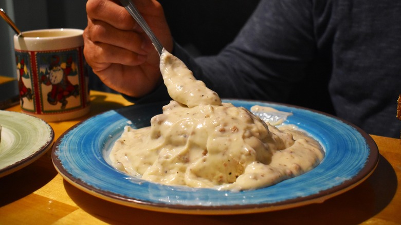 Person eating biscuits and gravy