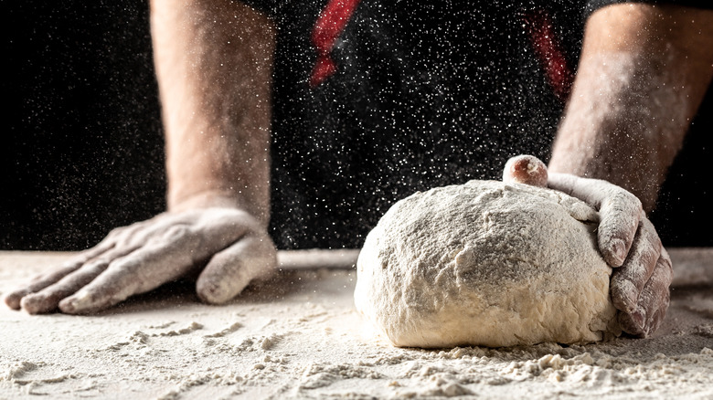 a man's hands rolling dough in flour