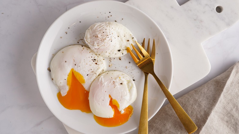 Three poached eggs on plate seasoned with pepper