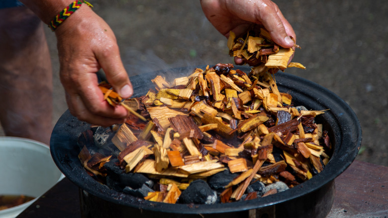 adding wood chips to coals