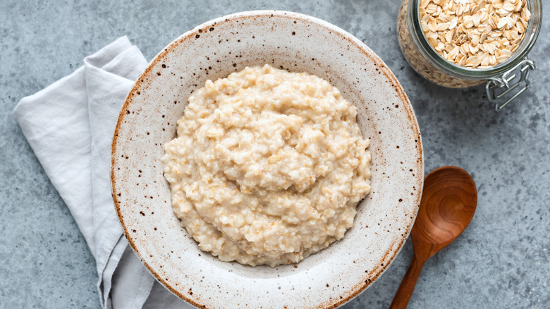 plain oatmeal in a bowl with a wooden spoon