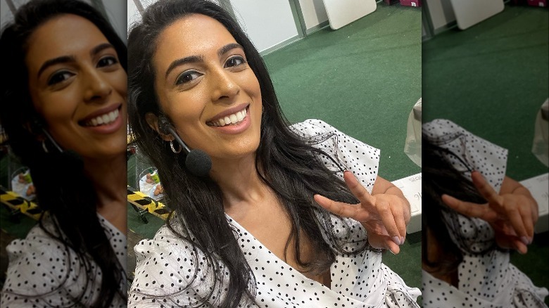 Crystelle Pereira smiles and gives peace sign 