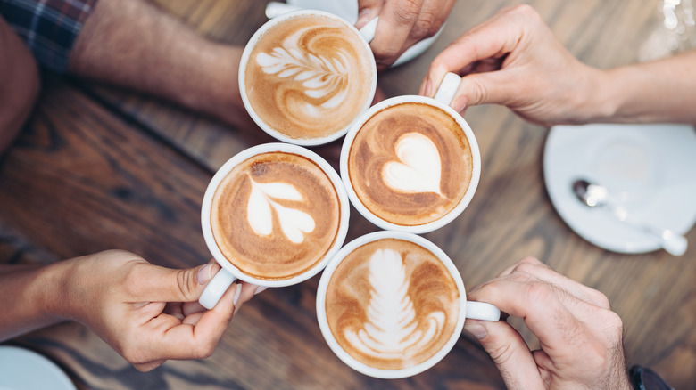 A group of hands holding coffee cups