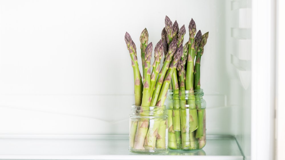 asparagus stalks standing in jar in fridge