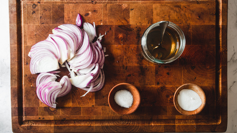 onions cut into slivers, vinegar, salt and sugar on cutting board