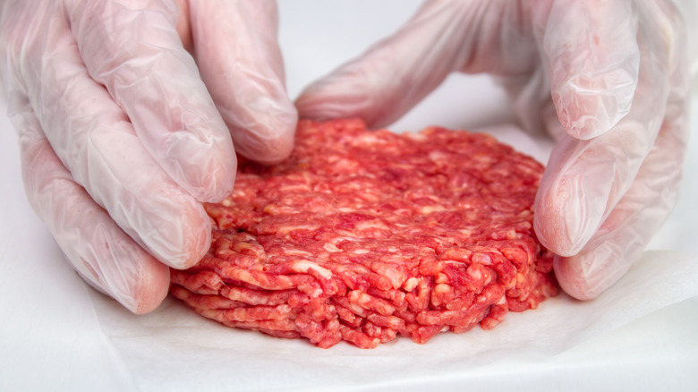 Hands shaping raw burger