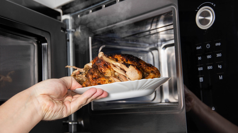 person putting chicken in microwave