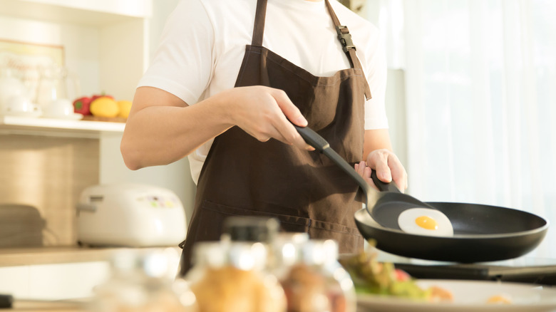 Person cooking a sunny side up egg in a pan