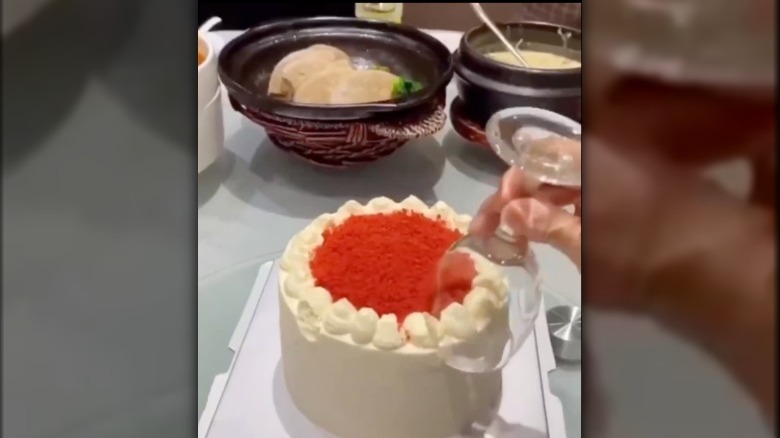 Wine glass being used to cut cake 