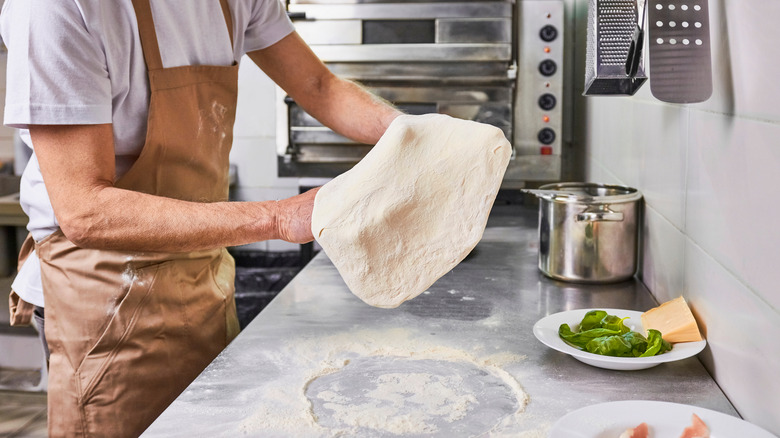 chef tossing pizza dough in commercial kitchen