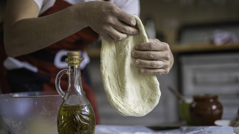 person stretching pizza dough by hand