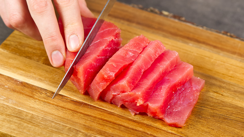 Person cutting raw tuna into sashimi