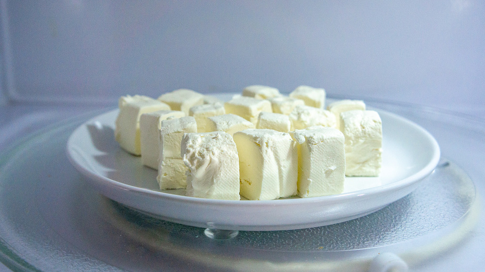 a plate of cut up cream cheese in a microwave