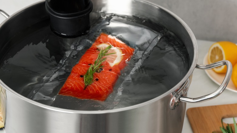 sealed salmon in sous vide cooker with lemons in background