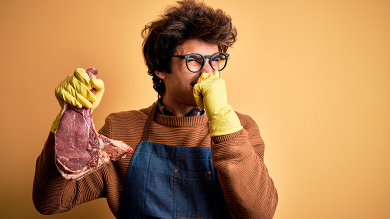 Man holding nose from bad smell of meat