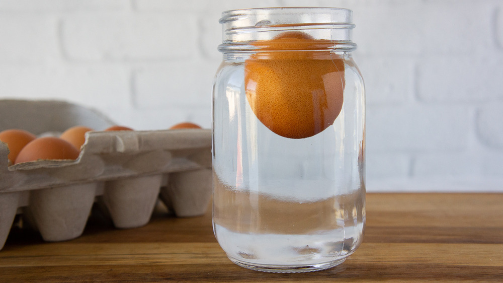 an egg floating in a mason jar of water