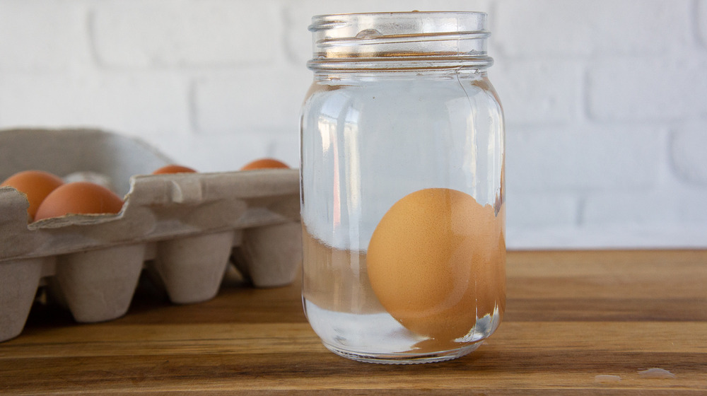 an egg standing on one end in a mason jar of water