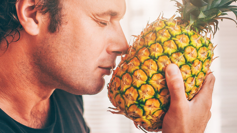 A person smelling a pineapple 