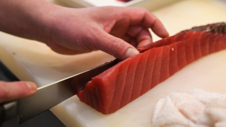 Sushi chef cutting tuna