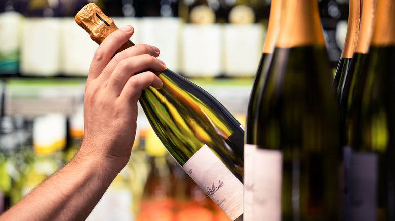 Hand taking bottle of prosecco from shelf