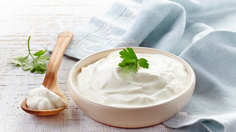 Sour cream in bowl with herb garnish