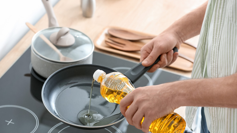 person pouring oil in pan 