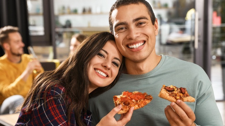 couple eating pizza and smiling
