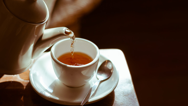 Pouring hot tea into cup 