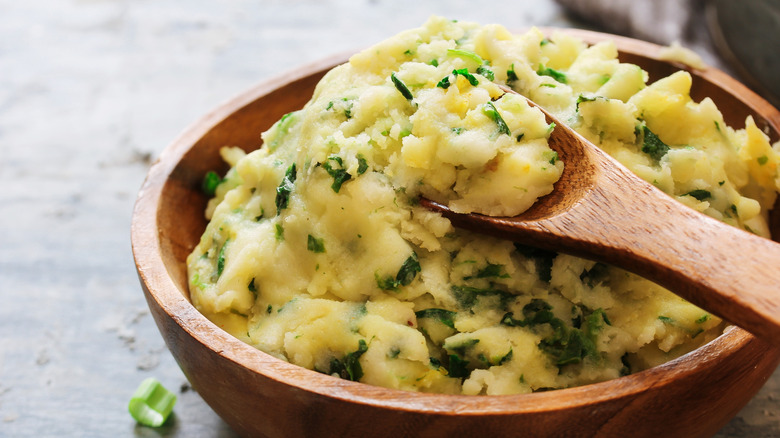 mashed potatoes with greens in wooden bowl