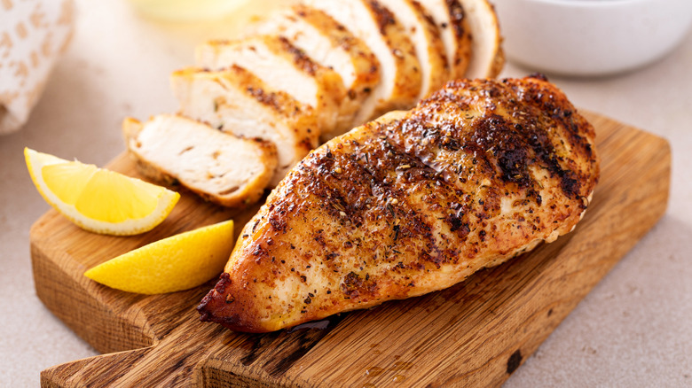 Grilled chicken on cutting board with slice of lemon