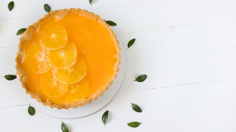 Sour orange pie surrounded by leaves on a white table