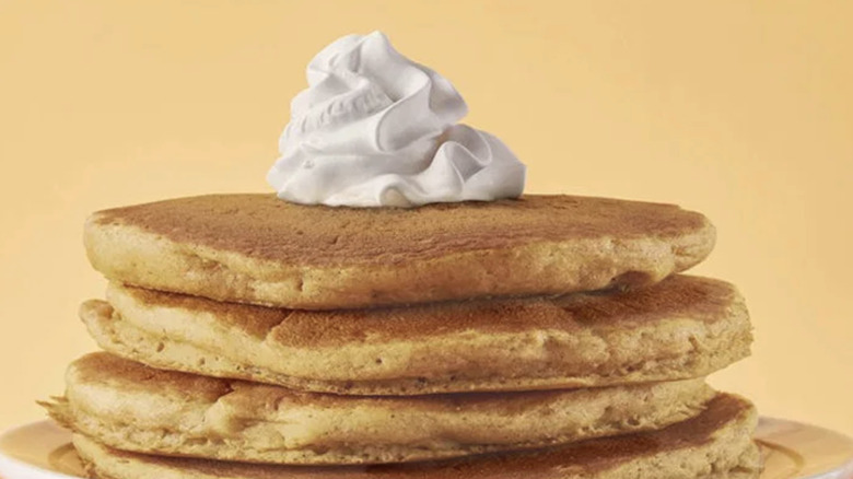 stack of four pumpkin pancakes with whipped cream