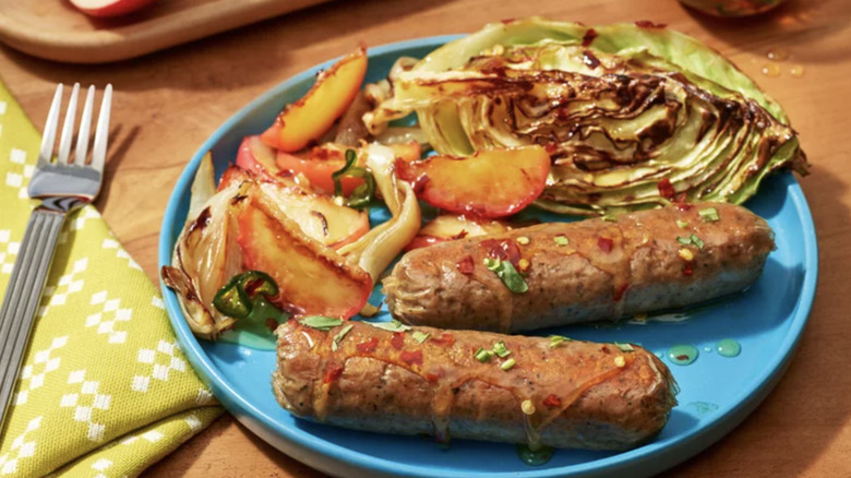 Grilled Impossible sausage on blue plate next to fork