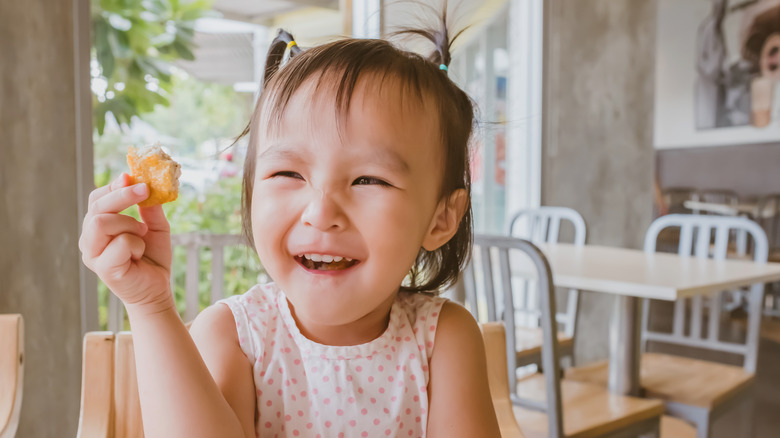 Child holding and chewing a nugget