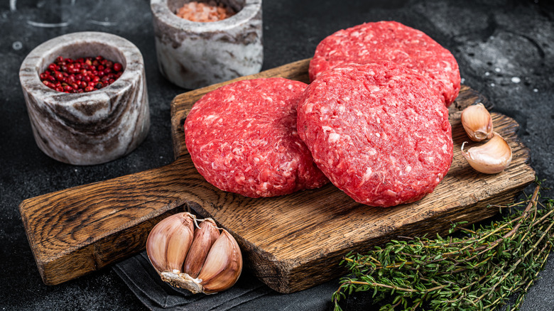 Burger patties surrounded by garlic and spices