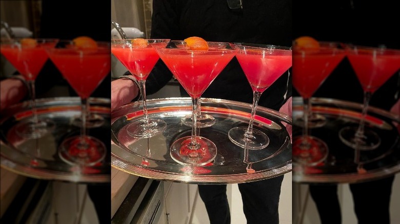 A silver tray of four blood orange cocktails in martini glasses