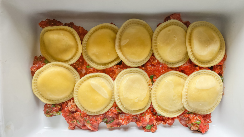 layering raviolis in a pan